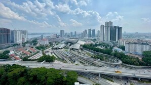 A cityscape with high-rise buildings, a complex highway interchange, and a clear sky. - Paragon Suites L18 By UCome Homestay (Johor Bahru)