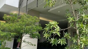 A modern building with a covered outdoor area featuring potted plants and a tree. - Paragon Suites L18 By UCome Homestay (Johor Bahru)