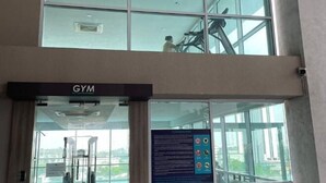 A gym entrance with a large glass window, a sign indicating the gym, and a view of the outside through the window. - Paragon Suites L18 By UCome Homestay (Johor Bahru)