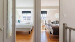 A bedroom with a wooden floor, a bed, a chair, and a window. - La Maison de Pierre et Valérie Saint Catherine (Honfleur)