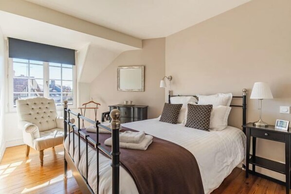A bedroom with a bed, bedside tables, a chair, a window, and a city view. - La Maison de Pierre et Valérie Saint Catherine (Honfleur)
