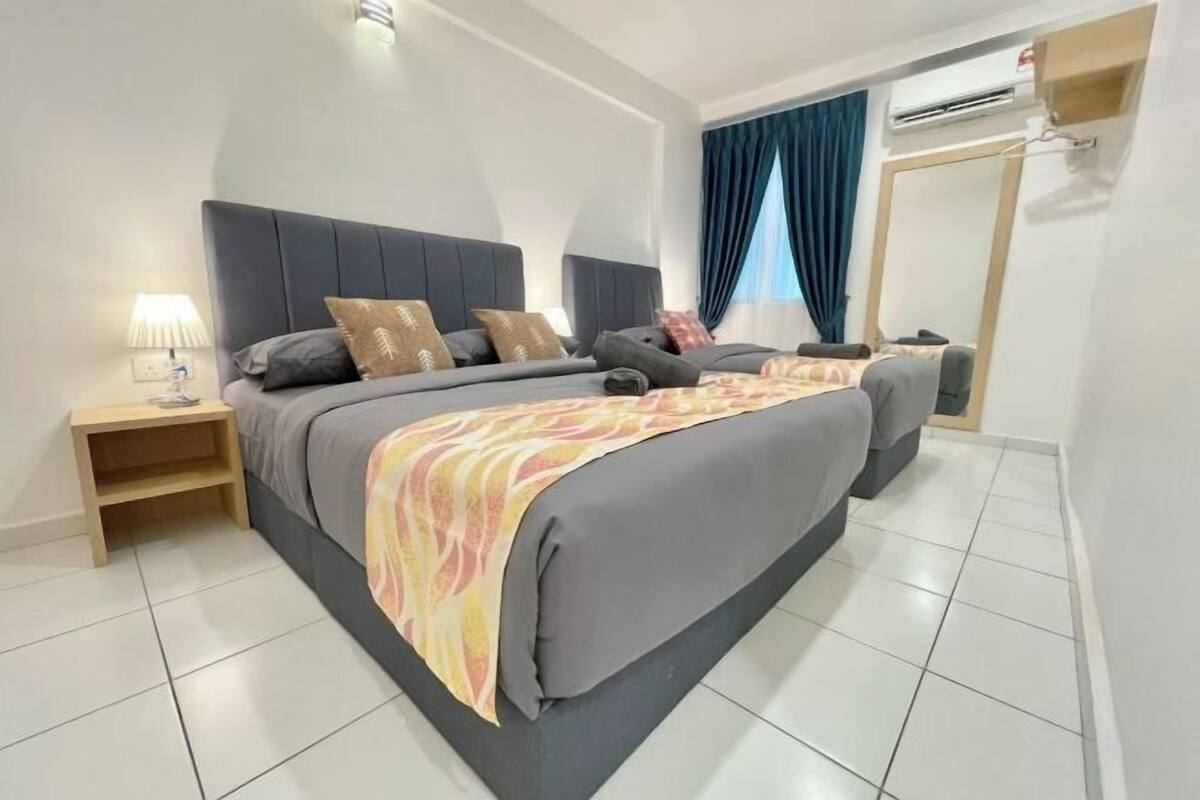 A modern hotel room with a large bed, bedside tables, a wardrobe, and an air conditioning unit.