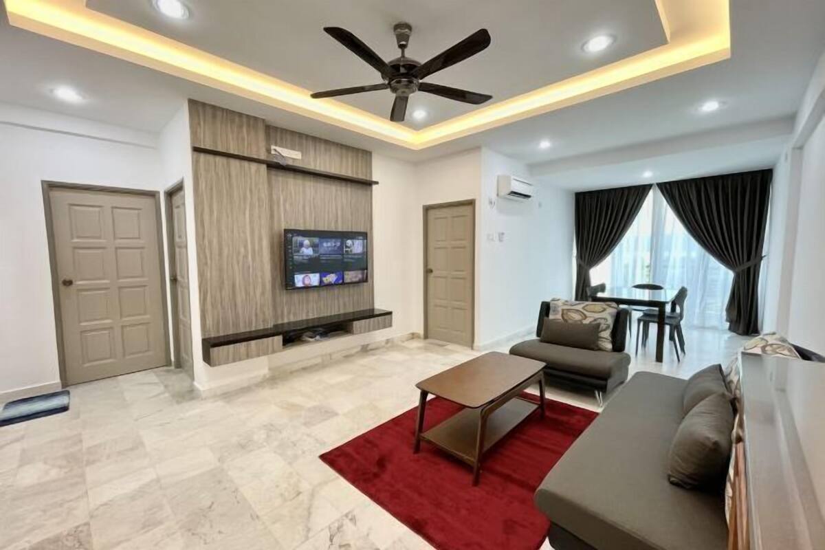 A modern living room with a flat-screen TV, a ceiling fan, a red rug, a sofa, and a dining area with a table and chairs.