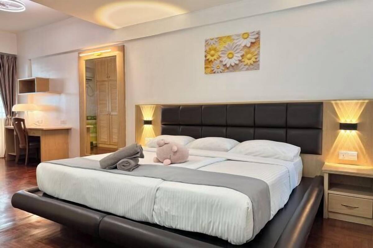 A neatly arranged bedroom with a bed, bedside lamps, a desk, and a chair.