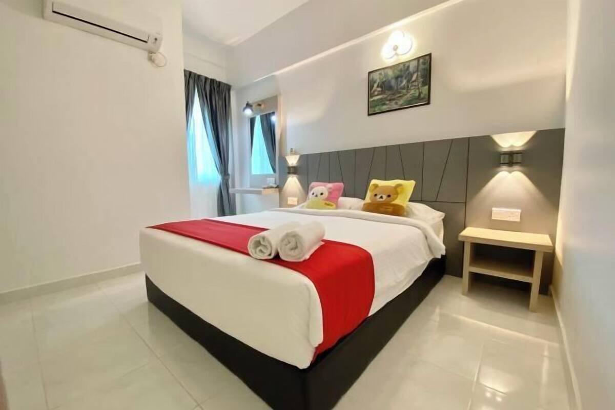A hotel room with a bed, bedside table, wall-mounted lamp, and a painting.