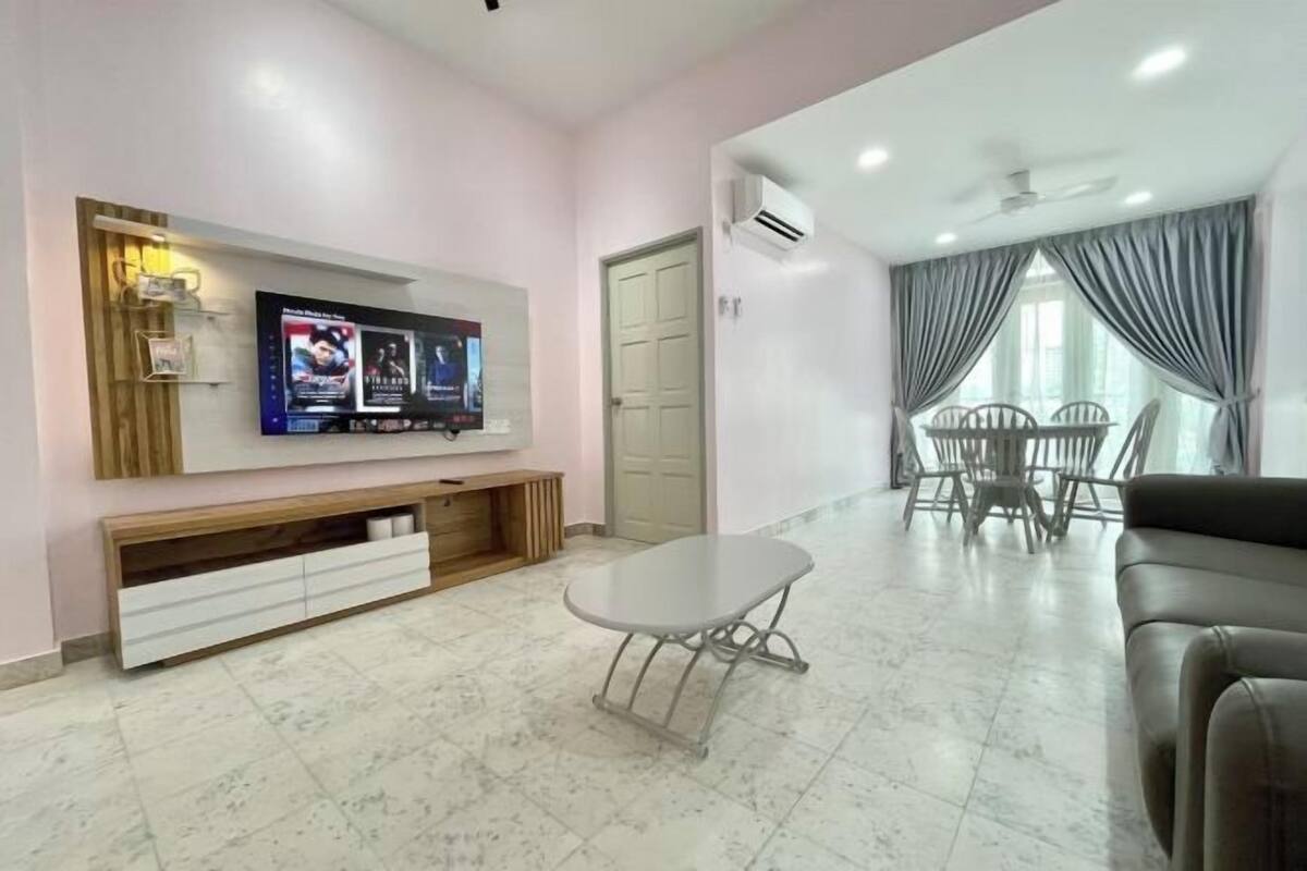 A modern living room with a flat-screen TV, a dining area with chairs, a sofa, and a small table.