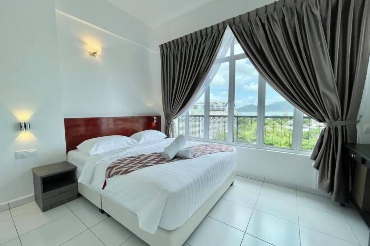 A modern hotel room with a large bed, a nightstand, a desk, and a view of the outdoors.