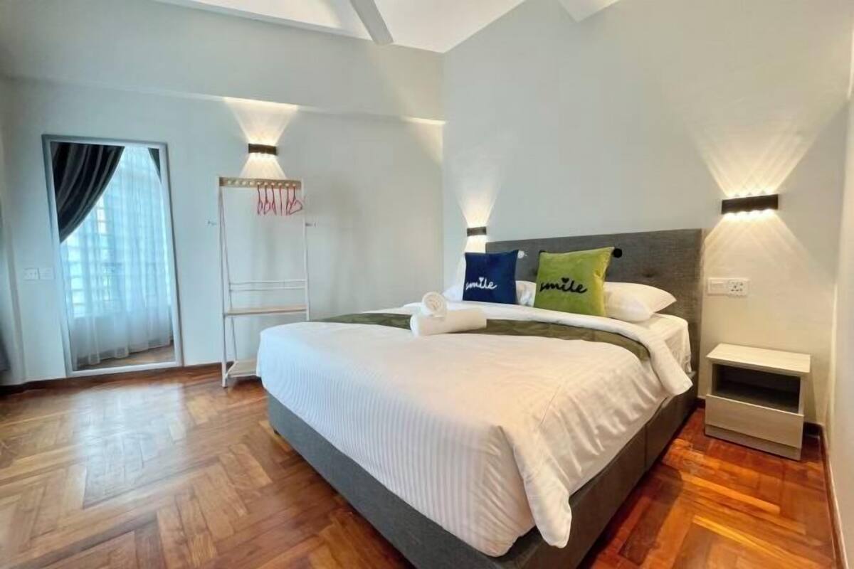 A bedroom with a large bed, bedside tables, a wardrobe, and a door with curtains.
