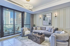 A modern living room with a large window, a sofa set, a coffee table, and a framed artwork on the wall.