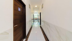 A hallway with a wooden door labeled "204", white walls, and a marble floor. - RedDoorz @ Lotus House Seminyak (Bali)