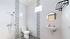 A bathroom with a shower, toilet, sink, and a mirror. - RedDoorz @ Lotus House Seminyak (Bali)
