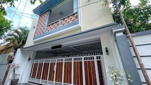 A two-story house with a gated entrance, a small balcony, and a potted plant near the entrance. - RedDoorz @ Lotus House Seminyak (Bali)