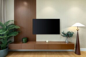 A modern living room with a flat-screen TV mounted on a wall, a wooden console table with a vase and candle, and a tall floor lamp. - Chic Downtown Living w Dubai Cityscape Views (Dubai)