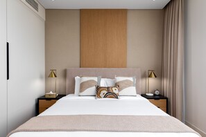 Een moderne hotelkamer met een groot bed, twee nachtkastjes met lampen, een houten wandpaneel en uitzicht op de stad.