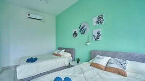 A hotel room with two beds, a small table, and wall art.