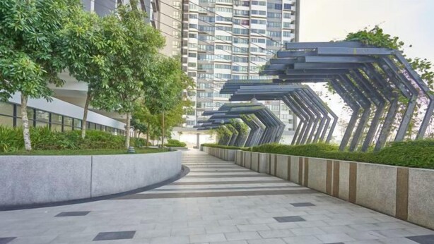 A modern urban pathway with a curved design, lined with greenery and a series of geometric metal structures.