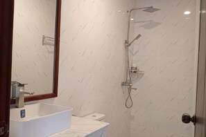 Un baño con un lavamanos blanco, un espejo y una ducha.