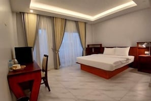 A hotel room with a bed, a desk, a chair, and a TV.