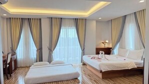 Una habitación de hotel con cama, mesitas de noche, escritorio y cortinas.