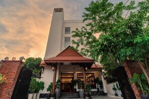 A building with a large entrance, a red-roofed pavilion, and a tall chimney. - Golden Sanctuary Boutique Hotel (Siem Reap)
