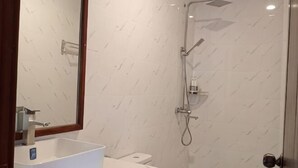 Un baño con lavamanos, espejo y ducha blancos.