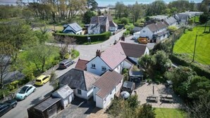 Un barrio residencial con casas, una calle, coches estacionados y vistas al mar.