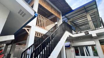 A multi-level building with a staircase, balconies, and a covered outdoor area.