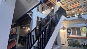 A multi-level building with a staircase, outdoor seating area, and a shop named "Sunny Terrace". - Sunny Terrace (Baler)
