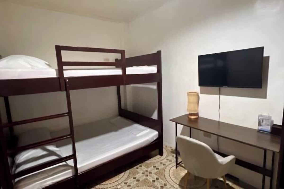 A bunk bed with a desk and chair, a television, and a lamp.