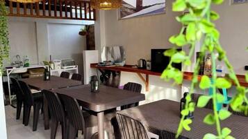 A dining area with a table and chairs, a kitchen area with appliances, and a TV.