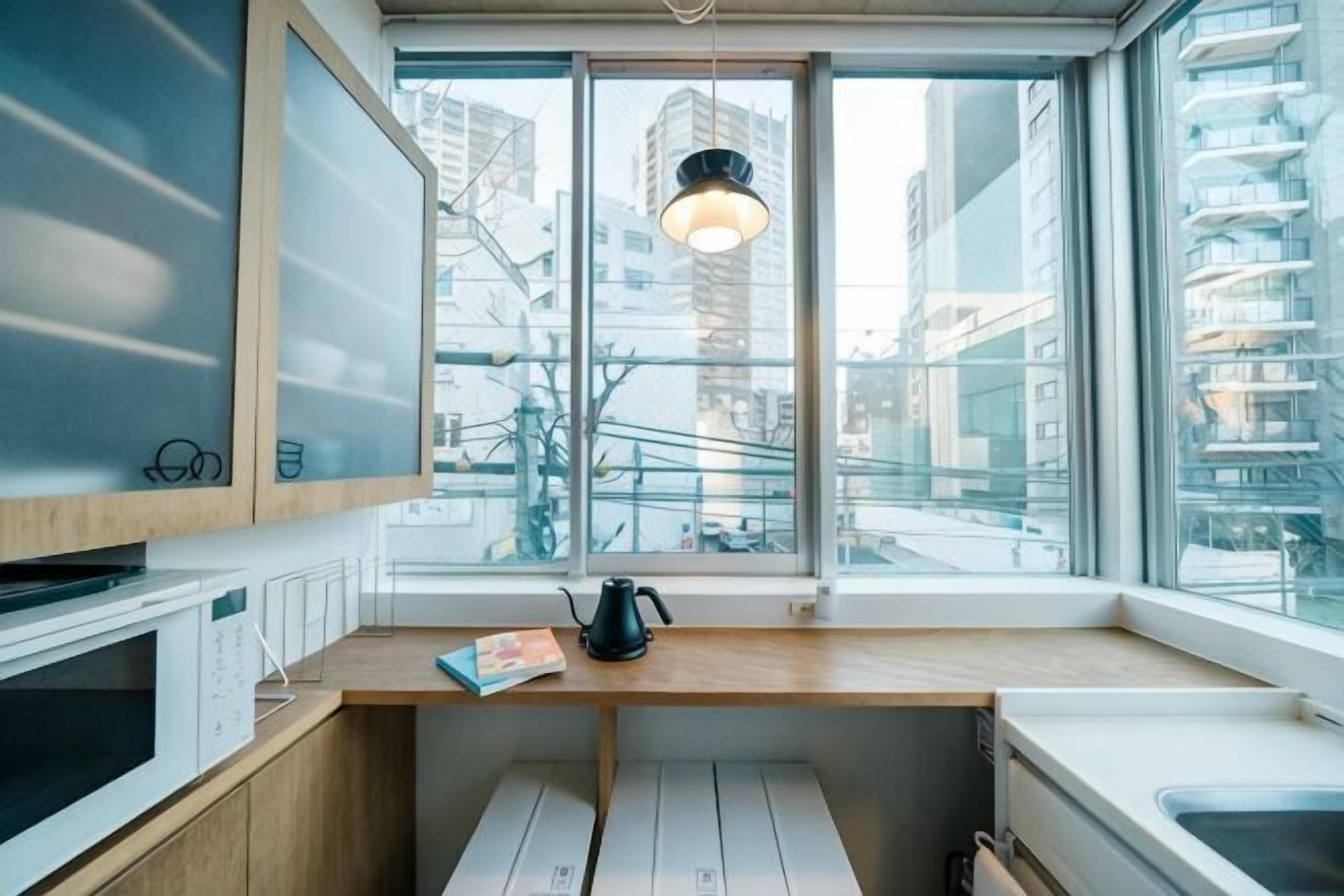A modern kitchen with a window, wooden countertop, and a kettle.