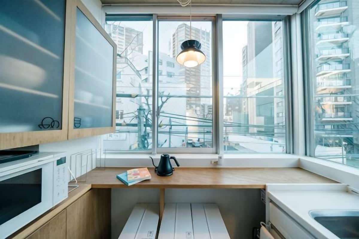 A modern kitchen with a window, wooden countertop, and a kettle.