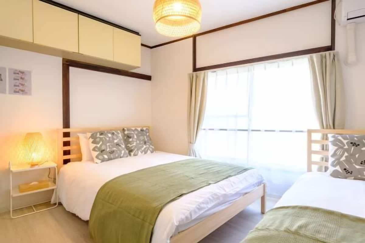 Une chambre d’hôtel avec un lit, une table de chevet, une lampe et une fenêtre avec des rideaux.
