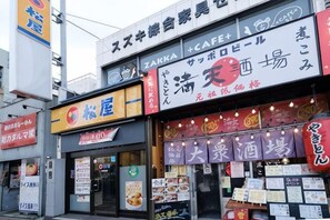 A row of storefronts with signs in Japanese, including one for a cafe and another for a restaurant. - Akisapo Stay Motohasunuma (Tokyo)