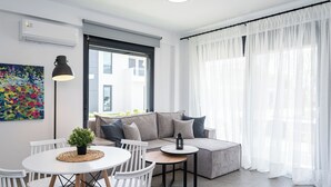 Ein modernes Wohnzimmer mit einer Couch, einem kleinen runden Tisch und einem Esstisch mit Stühlen.