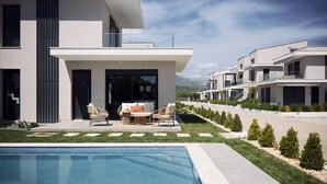 Ein modernes Wohngebäude mit Pool, Sitzgelegenheiten im Freien und Blick auf die Berge.