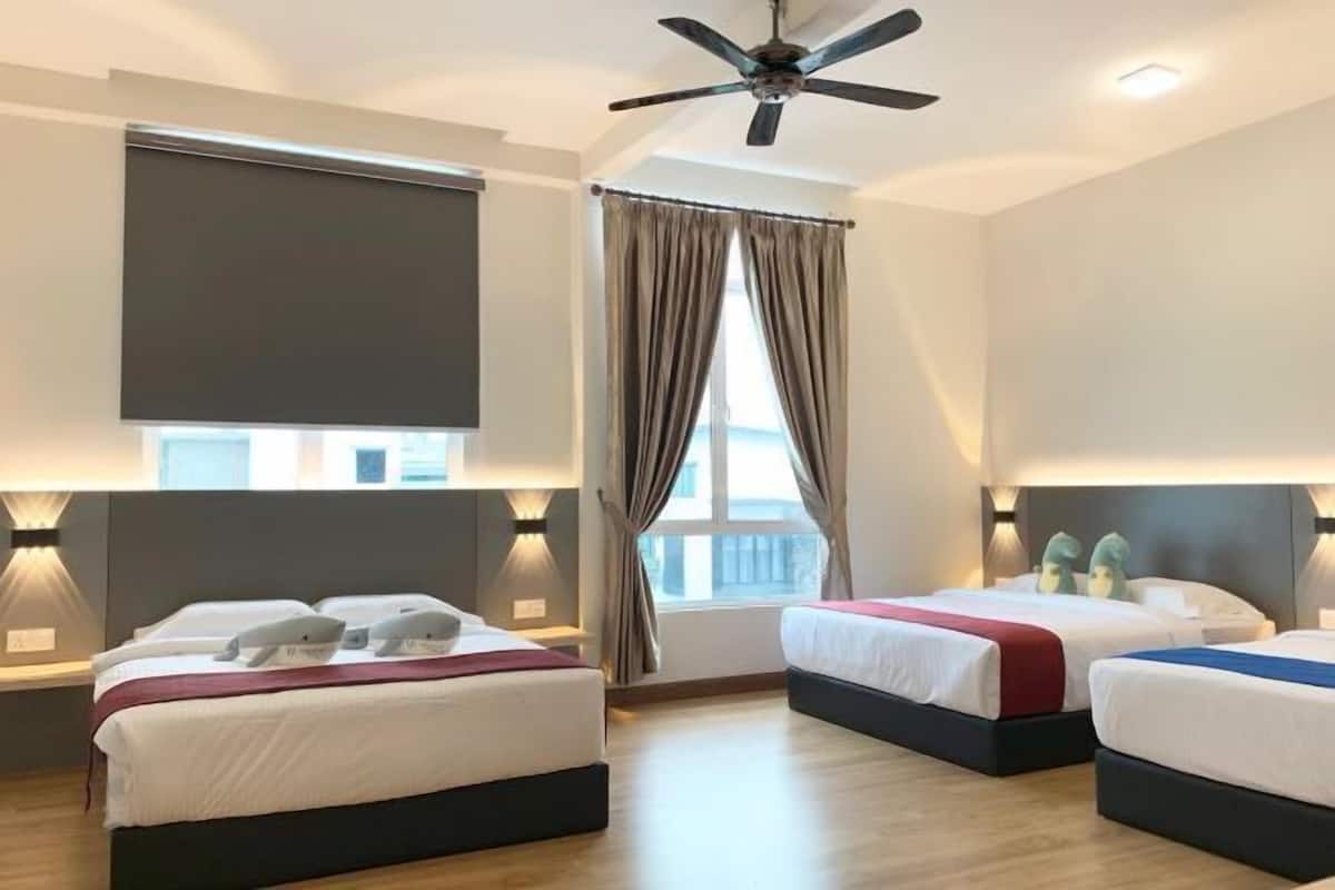 A hotel room with two beds, a ceiling fan, a large window with curtains, and a wall-mounted TV.