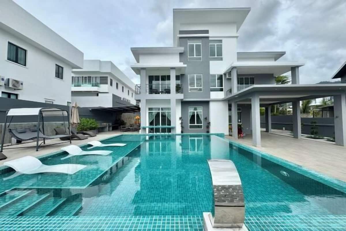 A modern building with a swimming pool, multiple balconies, and a covered outdoor area.