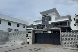 A modern multi-story residential building with a gated entrance and a covered driveway.
