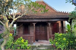 A traditional brick house with a tiled roof, wooden doors, and a small porch. - Munay Villa (Bali)