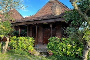 A traditional house with a tiled roof, wooden pillars, and a front porch. - Munay Villa (Bali)
