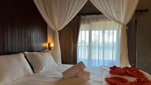 A hotel room with a bed, curtains, and a window. - Munay Villa (Bali)