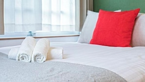 A neatly made bed with rolled white towels, a red pillow, and a white pillow. - Tabitime Teradacho - 5 min to JR station~grand new house~max 8ppl (Osaka)