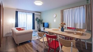 A modern living room with a sofa, dining table, and chairs. There is a television and a plant on the table. - Tabitime Teradacho - 5 min to JR station~grand new house~max 8ppl (Osaka)