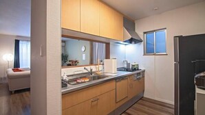 A modern kitchen with wooden cabinets, a stainless steel sink, and a black refrigerator. - Tabitime Teradacho - 5 min to JR station~grand new house~max 8ppl (Osaka)