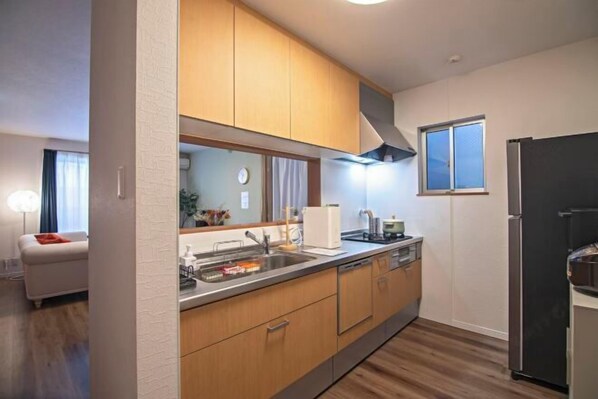 Una cocina moderna con armarios de madera, un lavamanos de acero inoxidable y un refrigerador negro.