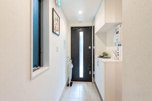 A narrow hallway with a door at the end, a radiator, and a shelf with items on the wall.