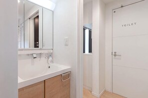 Un bagno con lavandino bianco, specchio e una porta con la scritta 'TOILET'.