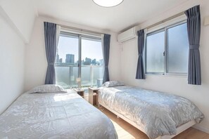 Une chambre avec deux lits, une fenêtre et une vue sur le paysage urbain.