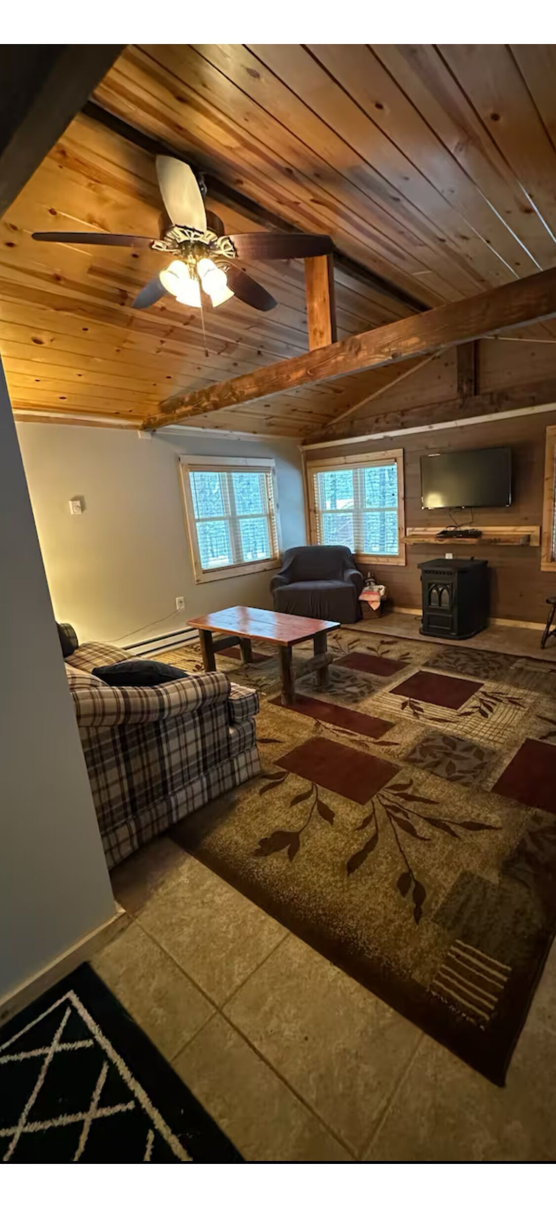 A cozy living room with a plaid sofa, a wooden coffee table, and a fireplace.